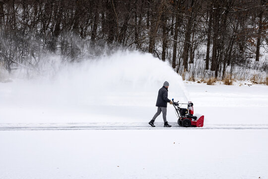 Wide shot of snowblowing ice rink on pond 