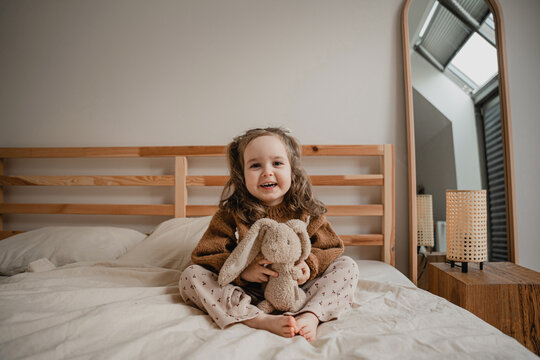 Little baby girl having cheerful leisure time in bed.
