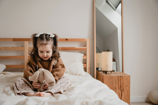 Little baby girl having cheerful leisure time in bed.