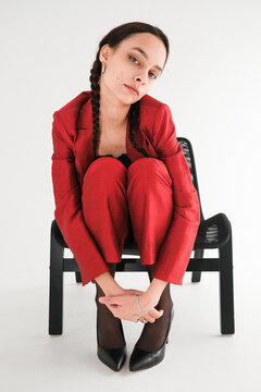 Model poses creatively in a red suit atop a black chair