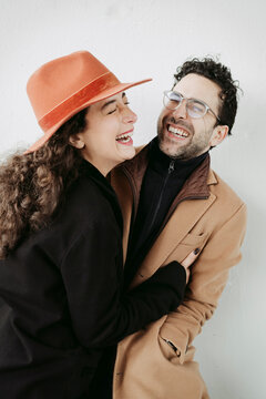 Couple laughing happily in front of a white wall