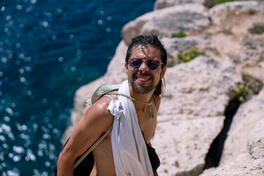 Young man smiling at a cliff beach