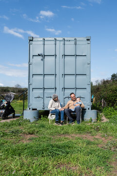 Family relaxing outside their shipping container home