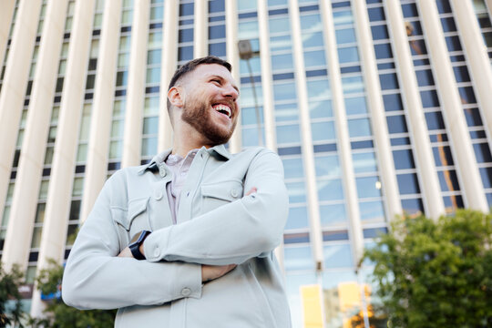 Gay man laughing confidently in front of a modern building