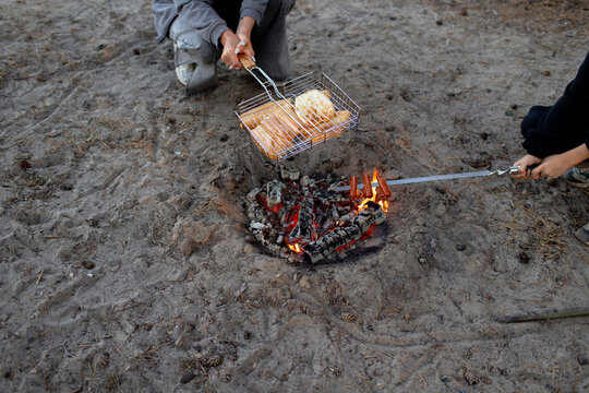 the family cooking hotdogs on a bonfire