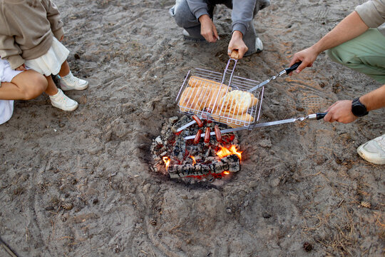 the family cooking hotdogs on a bonfire