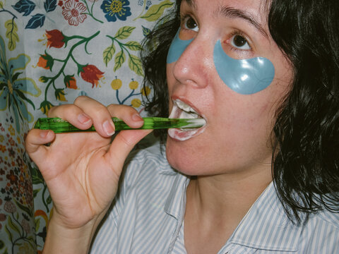 Woman with Eye Patches is Brushing her Teeth