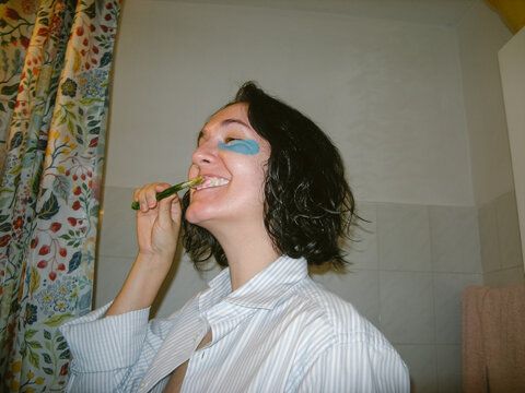Woman with Eye Patches is Brushing her Teeth
