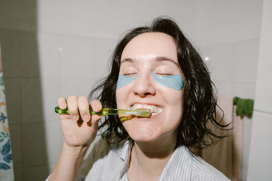 Woman with Eye Patches is Brushing her Teeth