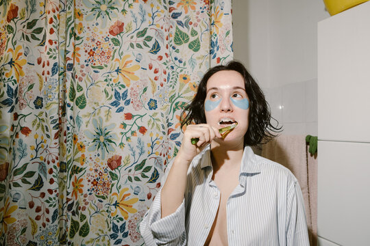 Woman with Eye Patches is Brushing her Teeth