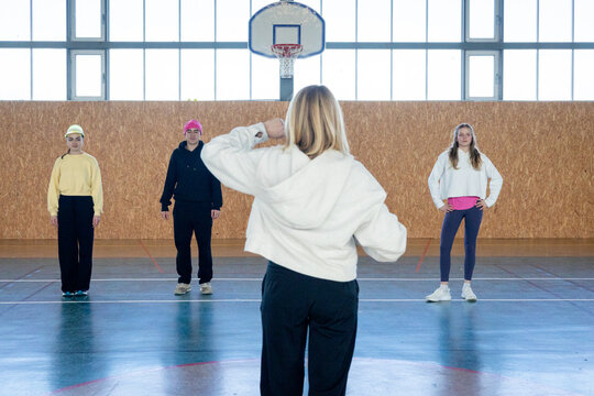 Gym class teacher talking with students before training