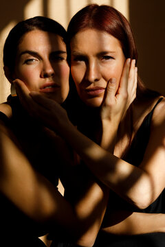 Two women embrace their faces