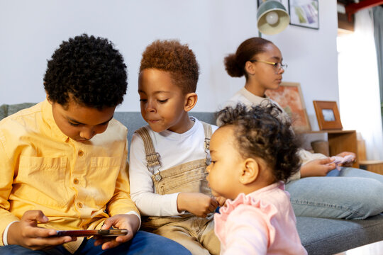 Group of kids playing on smartphone at home living room