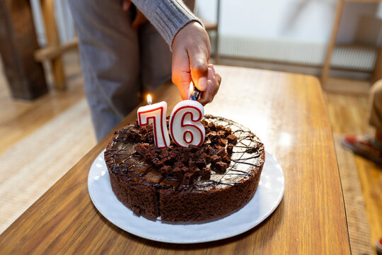 Anonymous girl's hand lighting cake candle at home living room