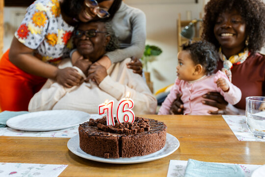 Grandma's 76th birthday on table while family's hugging grandma