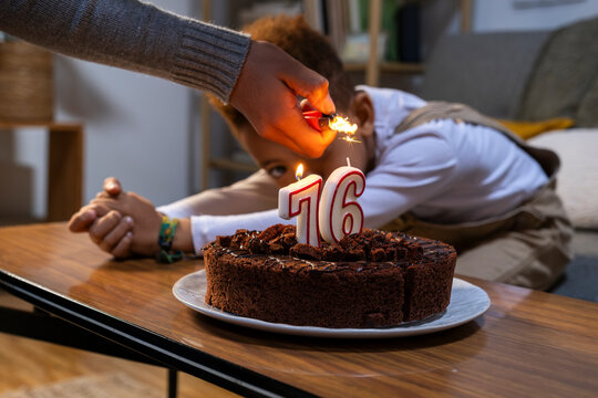 Anonymous girl's hand lighting cake candle while brother looks