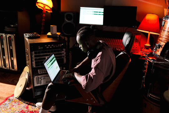 Man Producing Music on Laptop in Studio