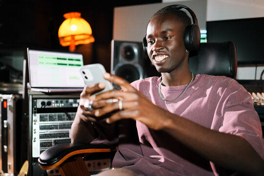 Man with Headphones Checking Phone in Studio