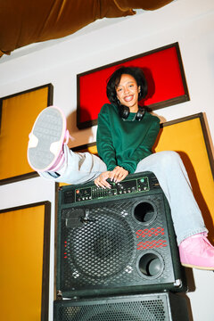 Playful woman sitting on large speakers