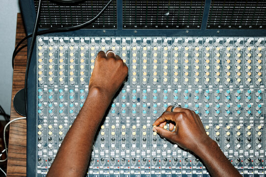 Hands Adjusting Audio Levels on Mixing Console