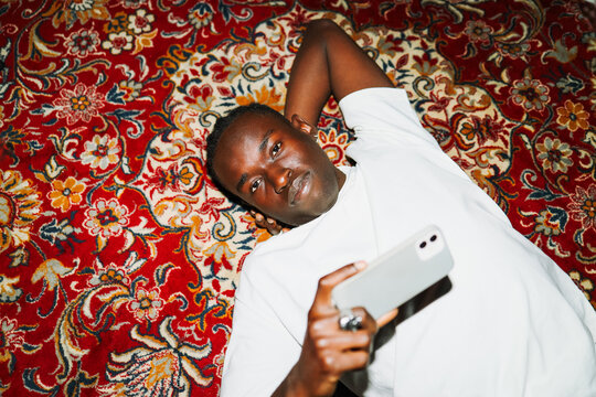Man lying on rug using phone