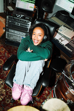 Smiling woman portrait enjoying music in studio chair