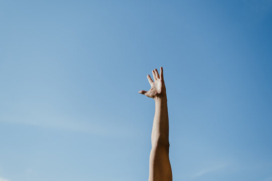 Hand reaching for the sky on a sunny day 