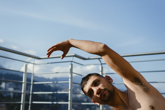 Young man stretching on a balcony with mountain view