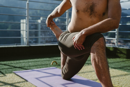 Yogi doing pigeon pose variation on rooftop at sunrise