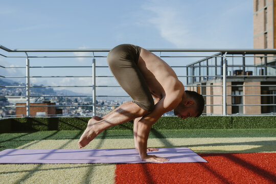Yogi practicing handstand posture on rooftop with city view