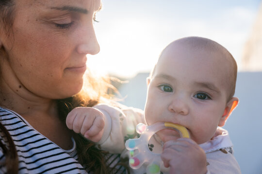 Mother holding her baby son chewing a teething ring