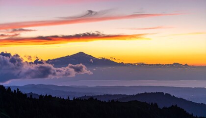 Fototapeta premium A vibrant sunrise illuminates the peaks of a mountain range. Purple and orange hues fill the sky as clouds cascade over the slopes