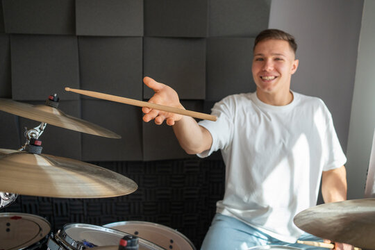 Smiling drummer holding a drumstick in a music studio