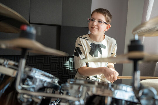 Smiling boy playing drum in recording studio