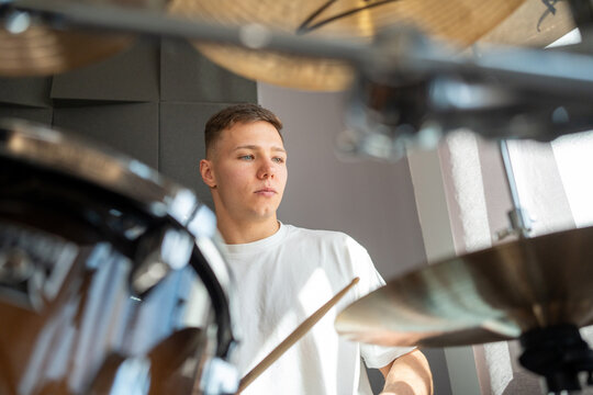 Focused drummer playing drum in studio