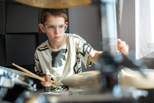 Focused boy playing drum set in studio