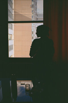 Silhouette of a woman looking out the window