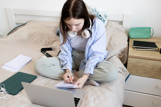a teenage girl sits with a notebook on the bed and teaches lessons