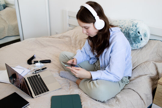 a teenage girl sits with a phone on the bed and teaches lessons