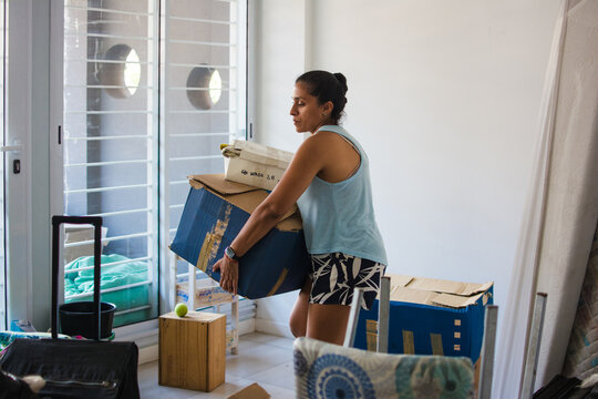 Strong latina woman lifting heavy boxes at home