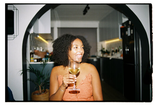 Woman with curly hair enjoying a beverage during dinner