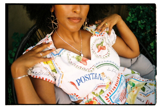 Woman with curly hair wearing jewelry and touching her shoulders