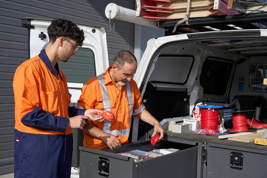 Workers organizing tools in service vehicle at construction site