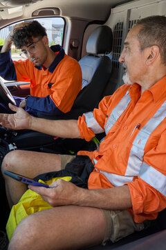 Workers discussing plans inside utility vehicle 
