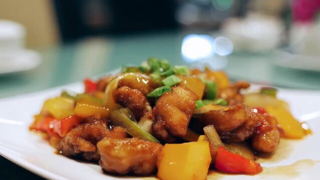 Golden Fried Sweet and Sour Pork Tenderloin in Vibrant Orange-Red Sauce, Crispy Batter Coating Glazed with Sticky Tangy Sauce, Garnished with Pineapple Chunks, Green Bell Pepper, and Onion. Classic Ch