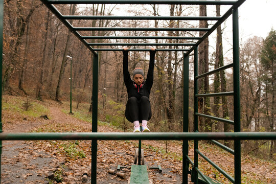 Woman Doing Abs Exercise on Monkey Bars in Outdoor Gym 
