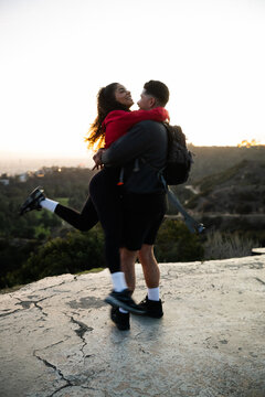 Couple Embracing Outdoors at Sunset with Joy and Happiness