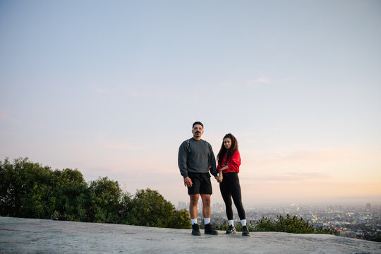 Couple Standing Outdoors with Scenic City View Holding Hands