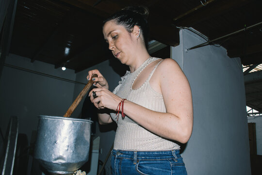 Woman stirring corn in grinding machine
