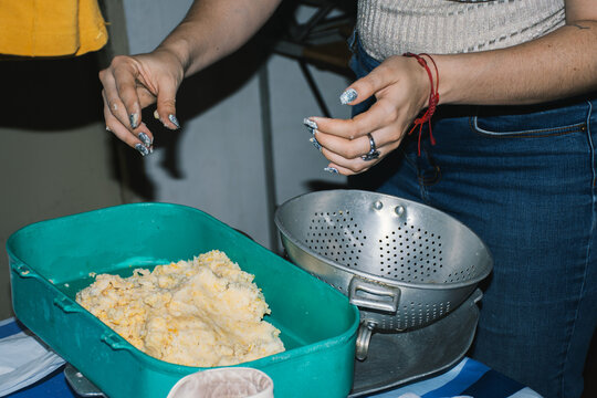 Woman picking up mashed corn from grinding machine